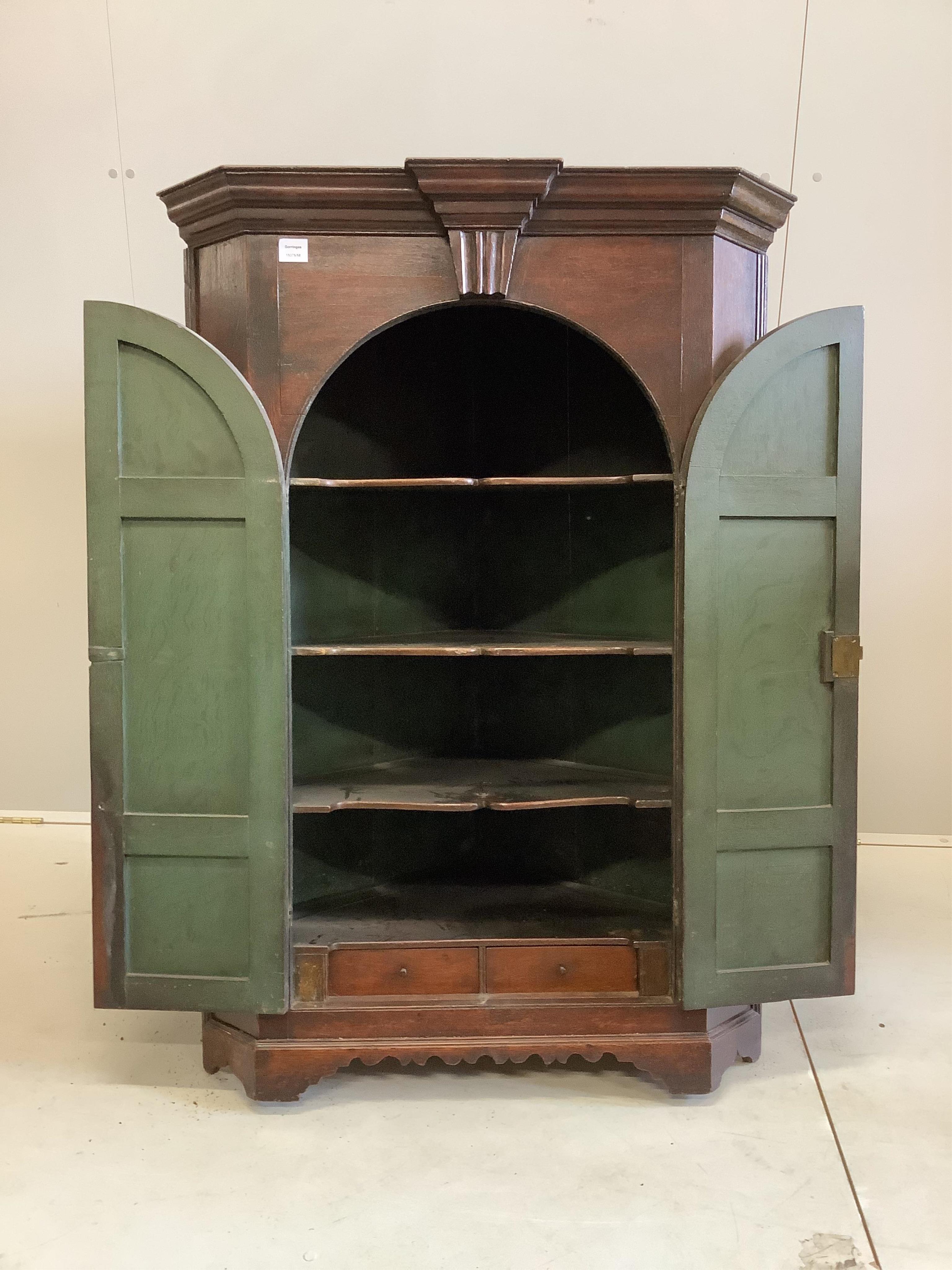 A George III oak hanging corner cupboard, enclosed by a pair of arched, fielded panelled doors, width 93cm, depth 59cm, height 134cm. Condition - fair